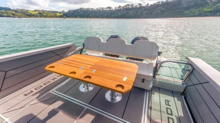 Slide: The Image of Saxdor 320 GTC 2025 boat with wooden table on deck, scenic water view. - 5