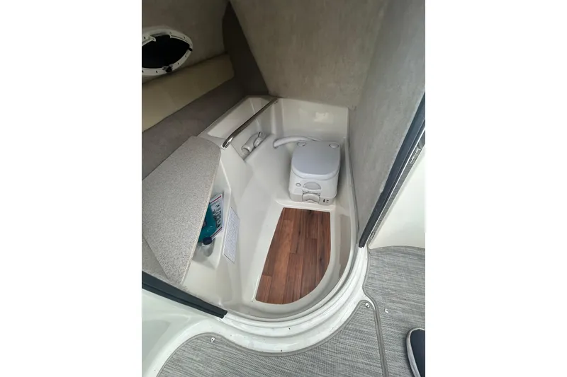 Slide: The Image of 2017 Stingray 235 LR boat interior with compact toilet and wooden flooring. - 10