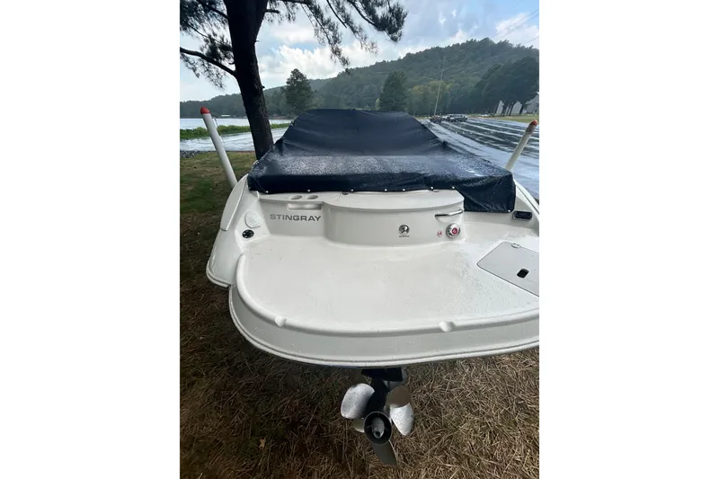 Slide: The Image of 2017 Stingray 235 LR boat with cover, parked near a scenic lake. - 4