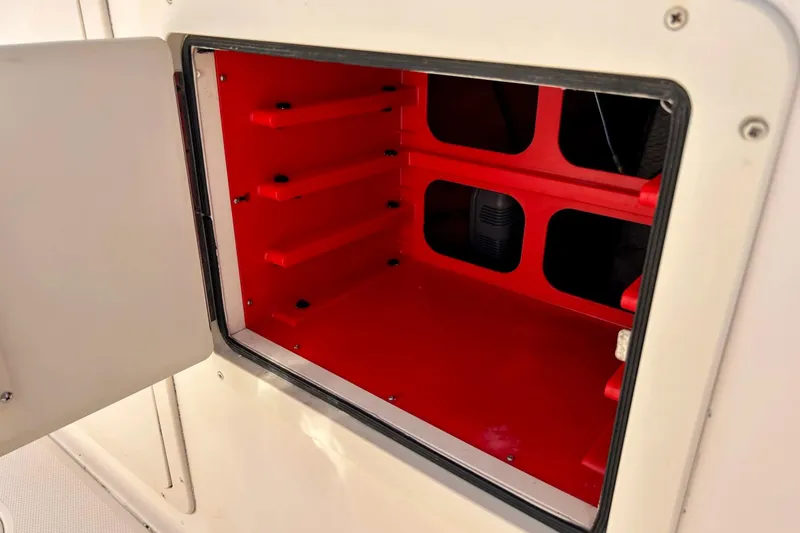 Slide: The Image of Open storage compartment on 2006 Grady White 225 Dual Console boat, featuring red interior shelves. - 38