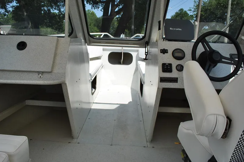 Slide: The Image of Interior of a 2009 Custom 24 boat with steering wheel and seating. - 14