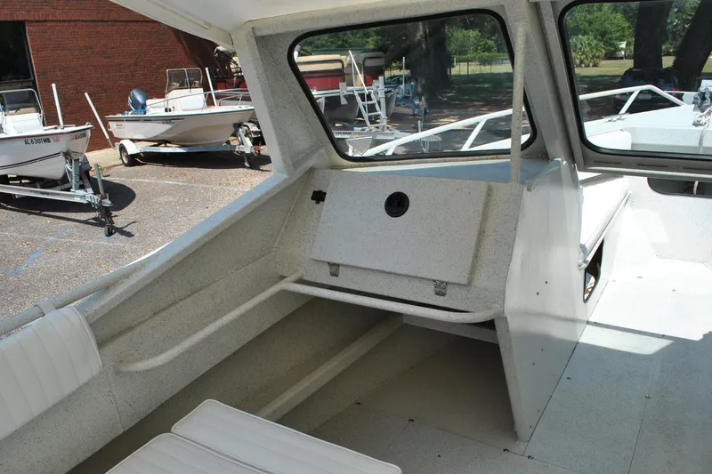 Slide: The Image of Interior of a 2009 Custom 24 boat, featuring seating and dashboard, parked near other boats. - 16