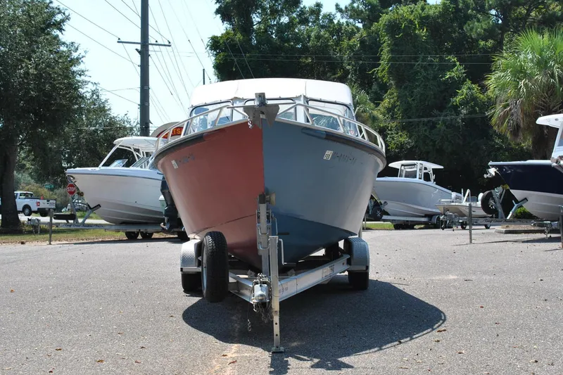 Slide: The Image of Custom 24 boat from 2009 on trailer, surrounded by trees and other boats. - 3