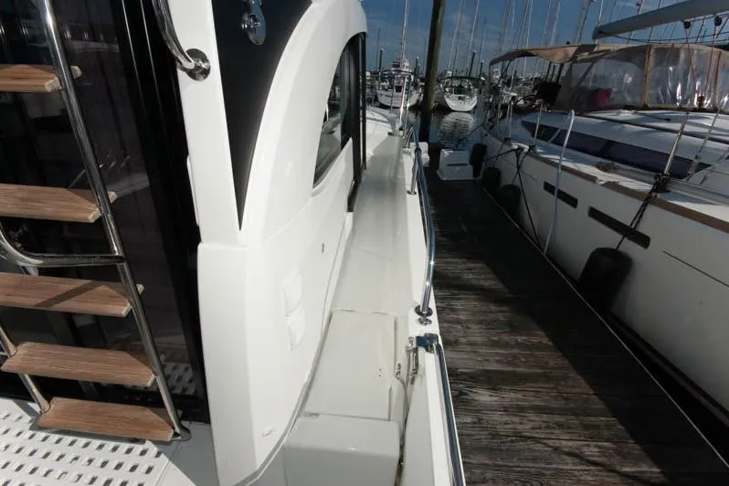 Slide: The Image of Interior of 2024 Beneteau Antares 11 Fly, featuring helm and cabin view with marina backdrop. - 8