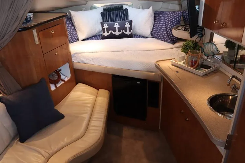 Slide: The Image of Cozy interior of 2002 Regal Commodore 2860 boat with bed, kitchenette, and seating area. - 13