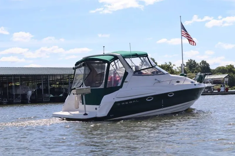 Slide: The Image of 2002 Regal Commodore 2860 boat cruising on a sunny day with American flag in background. - 2