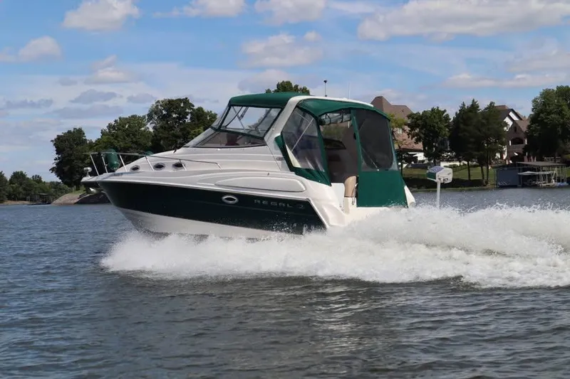 Slide: The Image of 2002 Regal Commodore 2860 boat cruising on a lake with scenic background. - 3