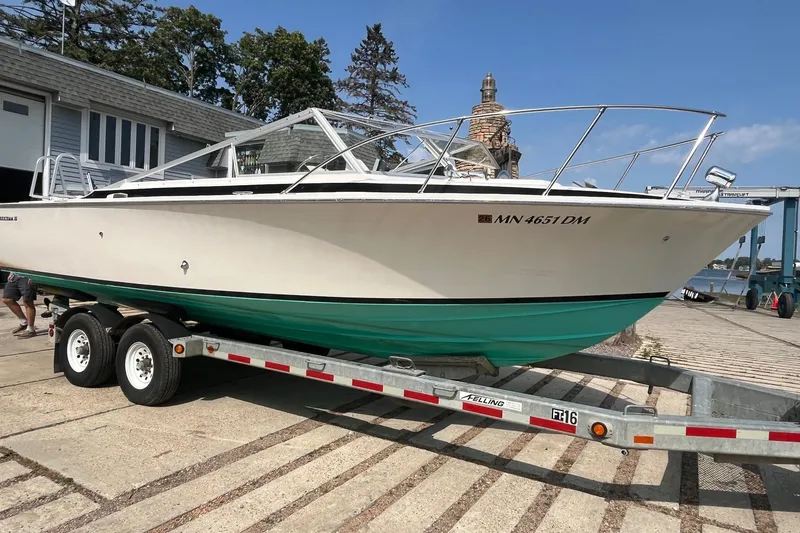 The Image of 1975 Bertram 26 Moppie boat on trailer, dockside, under clear blue sky. - 1