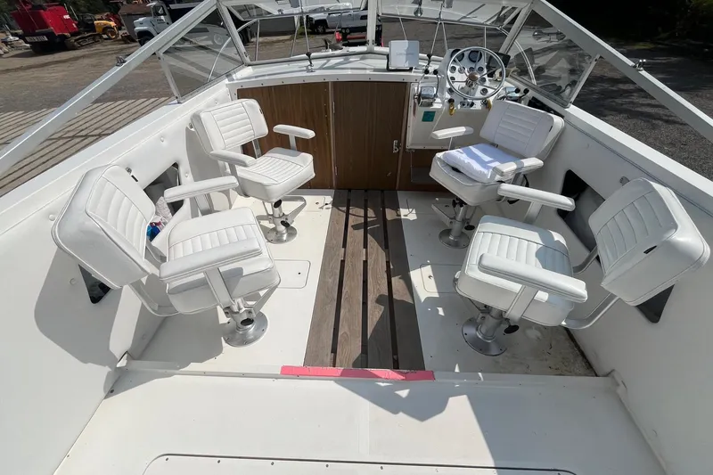 Slide: The Image of 1975 Bertram 26 Moppie boat interior with white swivel chairs and wooden flooring. - 10