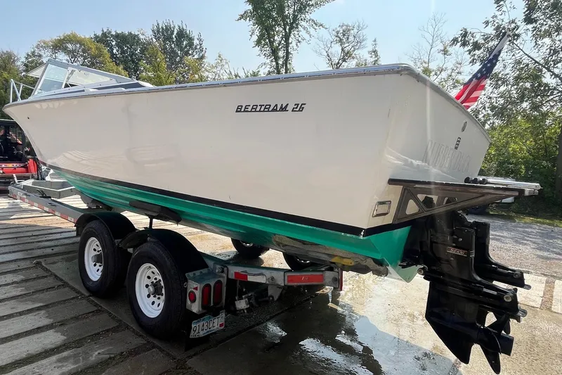 Slide: The Image of 1975 Bertram 26 Moppie boat on trailer, displayed outdoors with American flag. - 3