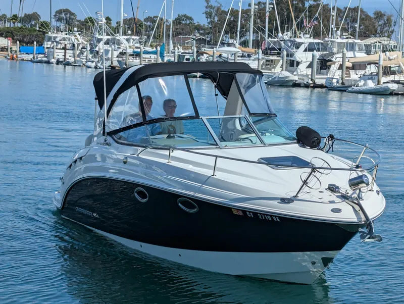 Slide: The Image of 2011 Chaparral Signature 270 boat cruising in a marina with other boats docked. - 11