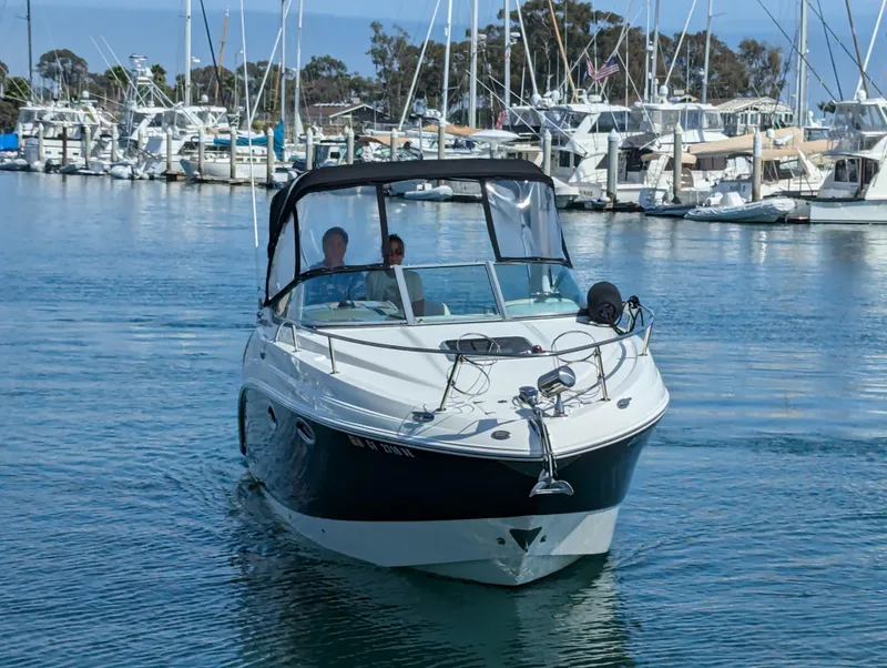 Slide: The Image of 2011 Chaparral Signature 270 boat cruising in a marina with other boats docked. - 12