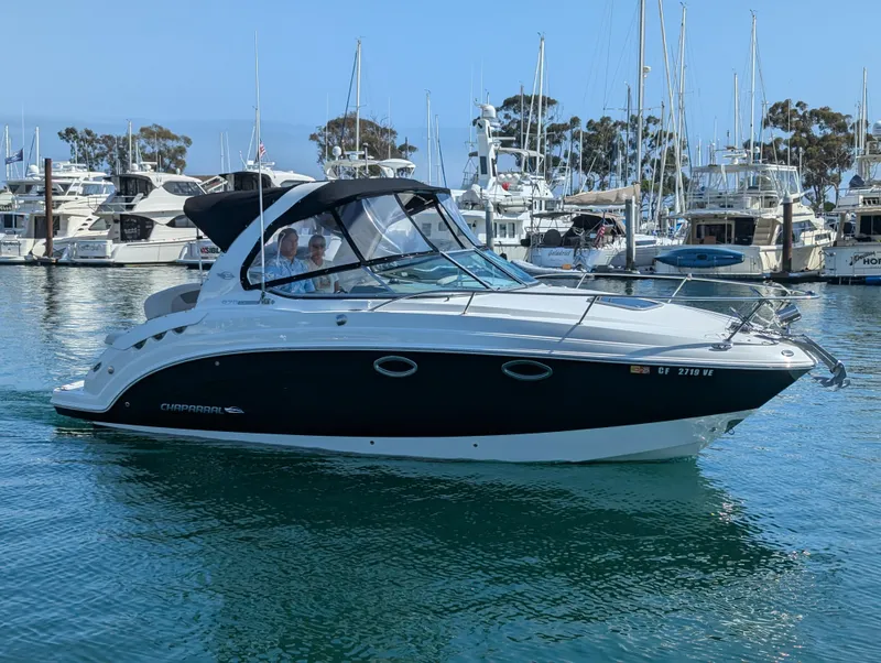 Slide: The Image of 2011 Chaparral Signature 270 boat cruising in a marina with docked yachts. - 2