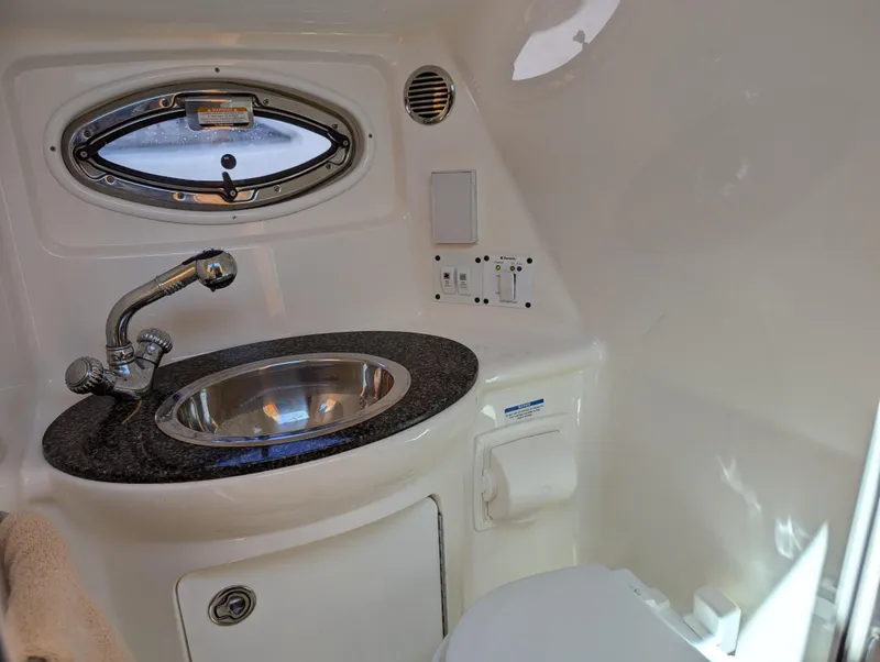 Slide: The Image of 2011 Chaparral Signature 270 boat bathroom with sink, faucet, and porthole window. - 37