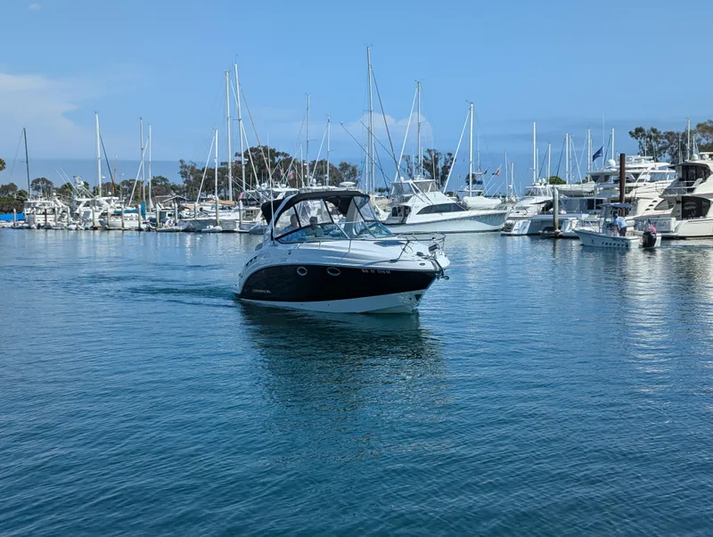 Slide: The Image of 2011 Chaparral Signature 270 boat cruising in a marina with sailboats in the background. - 6