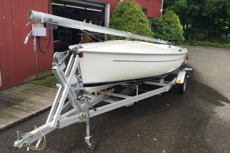 Slide: The Image of 2002 Flying Scot 19 sailboat on trailer, parked near a red building. - 0