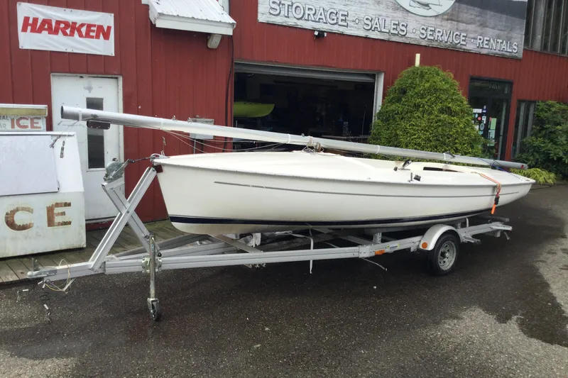 Slide: The Image of 2002 Flying Scot 19 sailboat on trailer outside a red building. - 2