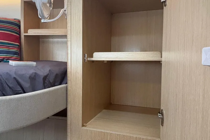 Slide: The Image of Interior of 2022 Seaway 1600 showing wooden cabinet and bed with striped pillow. - 44