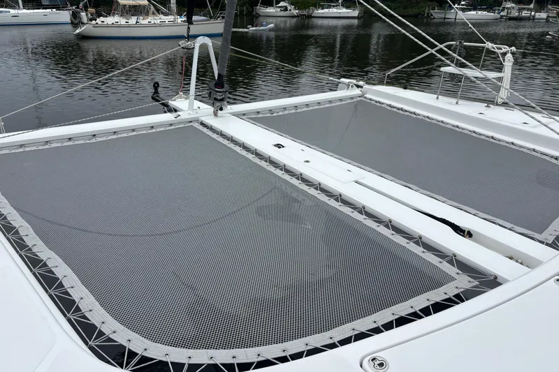 Slide: The Image of 2022 Seawind 1600 catamaran with netted deck, moored on a calm waterway. - 52