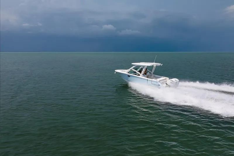 Slide: The Image of 2026 Robalo R257 Dual Console boat cruising on open water under cloudy skies. - 31