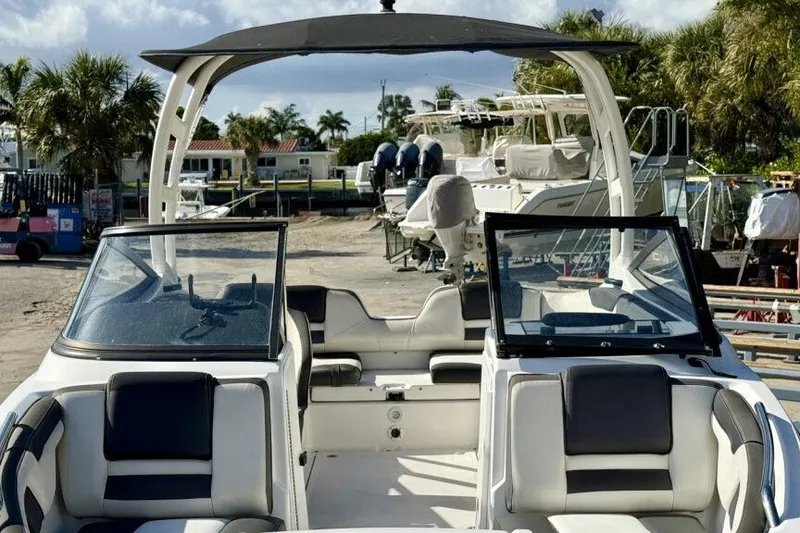 Slide: The Image of 2020 Yamaha Boats AR210 interior with seating, windshield, and canopy in a marina setting. - 19