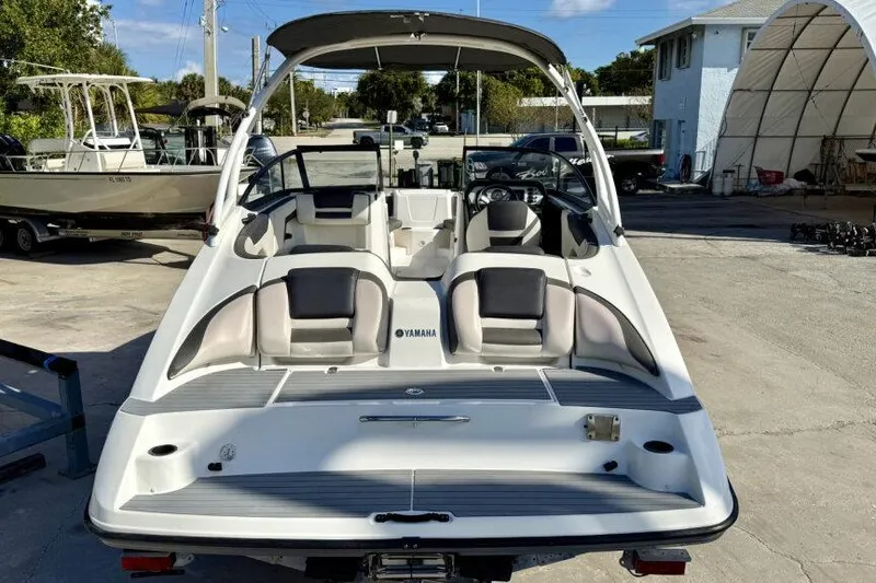 Slide: The Image of 2020 Yamaha Boats AR210, rear view, parked outdoors, showcasing seating and deck layout. - 21