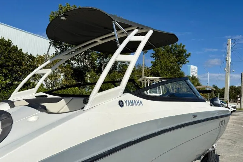 Slide: The Image of 2020 Yamaha AR210 boat with canopy, parked outdoors under clear blue sky. - 27