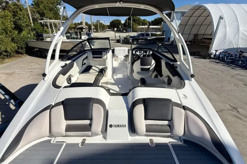 Slide: The Image of 2020 Yamaha Boats AR210 interior with seating and steering wheel, parked outdoors. - 31