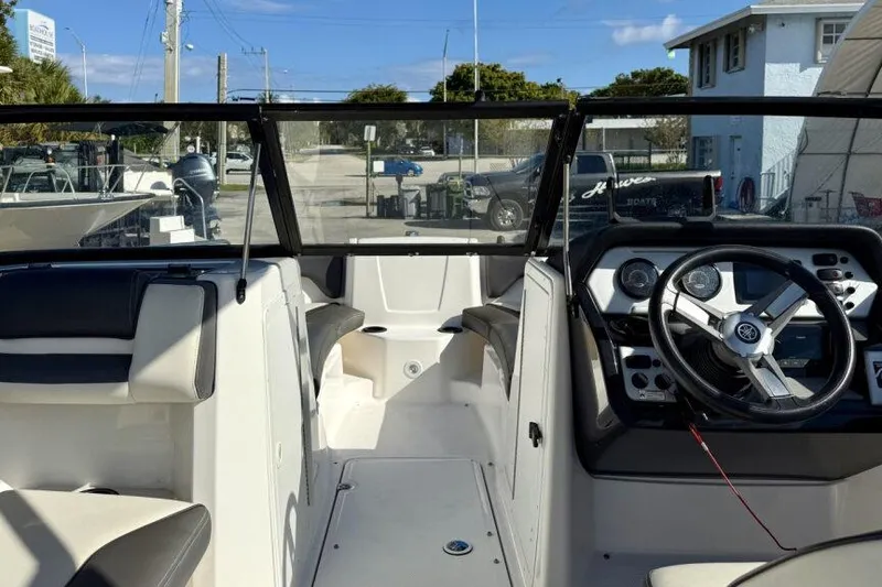 Slide: The Image of 2020 Yamaha Boats AR210 interior with steering wheel and seating, docked outdoors. - 36