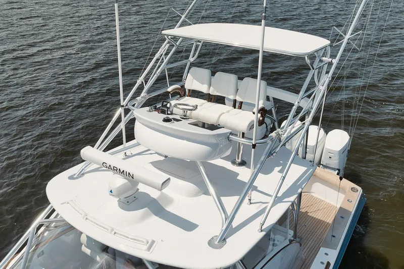 Slide: The Image of 2024 Gamefisherman 49 boat with elevated helm, Garmin equipment, and ocean backdrop. - 33