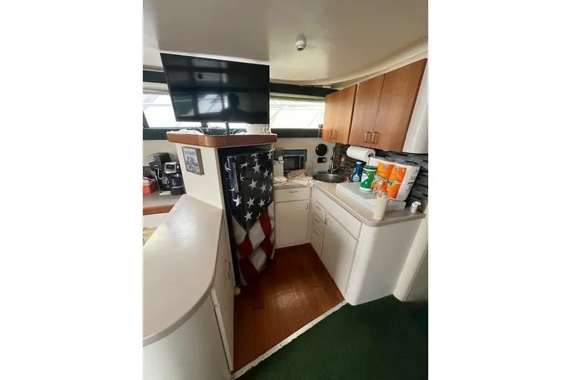 Slide: The Image of 1994 Mainship 40 Sedan Bridge interior kitchen with cabinets, sink, and American flag decor. - 11