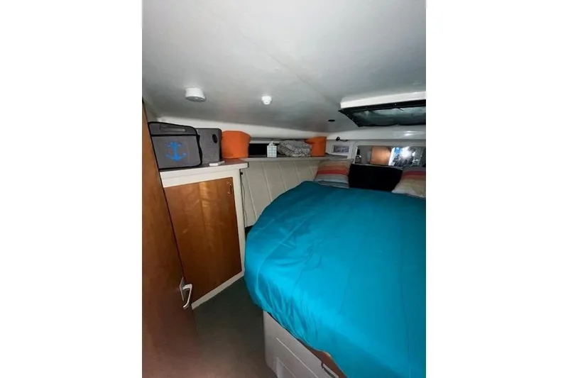 Slide: The Image of 1994 Mainship 40 Sedan Bridge cabin interior with blue bedding and storage shelves. - 13