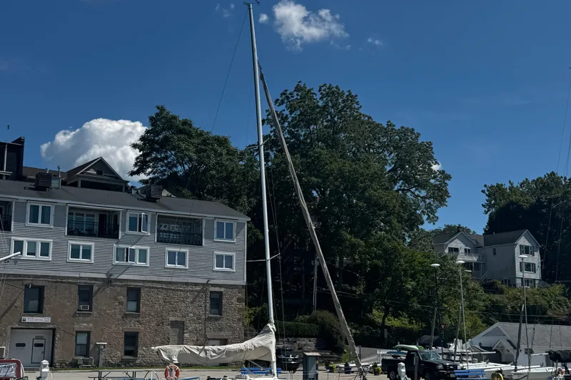 Slide: The Image of 2003 J Boats J/105 sailboat docked near waterfront buildings and trees. - 32