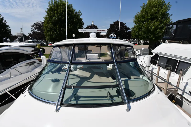 Slide: The Image of 2001 Sea Ray 540 Sundancer yacht docked, front view with clear windshield and trees in background. - 7