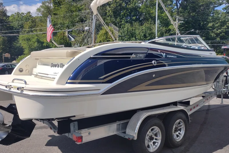 Slide: The Image of 2015 Formula 240 Bowrider boat on trailer, parked outdoors with trees in background. - 5