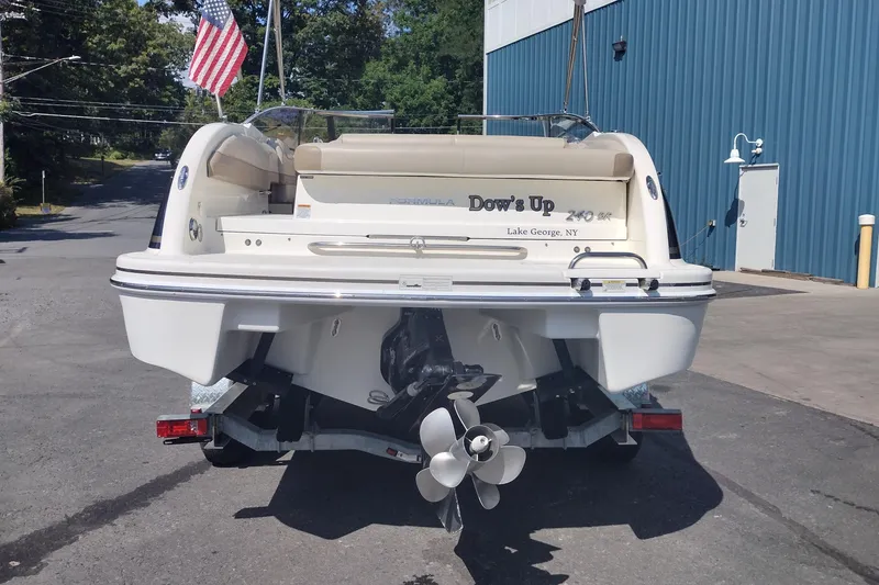 Slide: The Image of 2015 Formula 240 Bowrider boat with American flag, parked near blue building. - 6