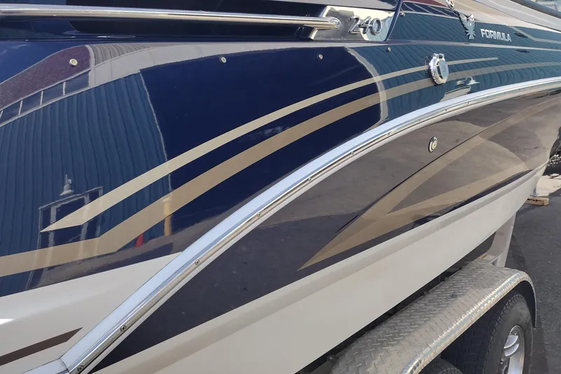Slide: The Image of 2015 Formula 240 Bowrider boat with sleek blue and beige design on trailer. - 9