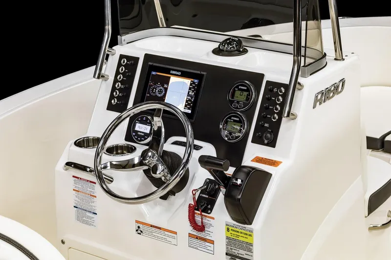 Slide: The Image of 2026 Robalo R180 Center Console boat dashboard with steering wheel and navigation controls. - 9