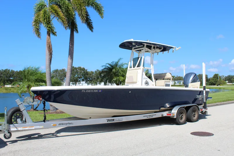 The Image of 2017 Pathfinder 2500 Hybrid boat on trailer, parked near palm trees and water. - 0