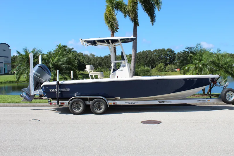 Slide: The Image of 2017 Pathfinder 2500 Hybrid boat on trailer, parked near palm trees and lake. - 3