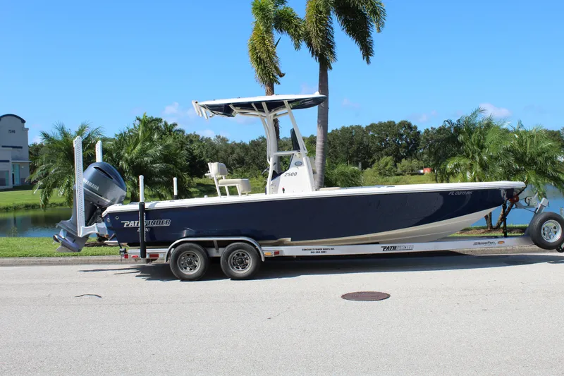 Slide: The Image of 2017 Pathfinder 2500 Hybrid boat on trailer, parked near palm trees and water. - 5