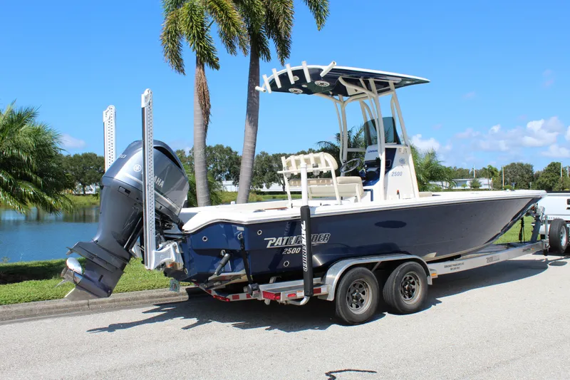 Slide: The Image of 2017 Pathfinder 2500 Hybrid boat on trailer, parked near palm trees and water. - 9
