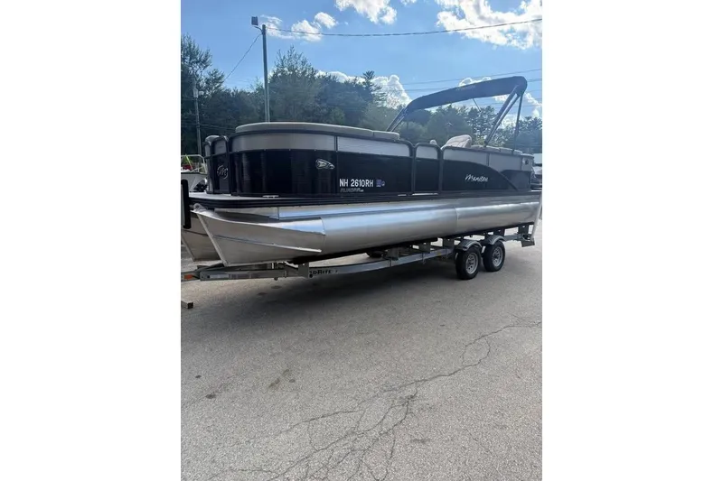 Slide: The Image of 2022 Manitou 23 Aurora LE RF pontoon boat on trailer, parked outdoors. - 0