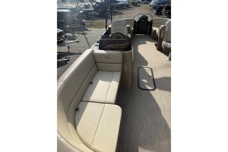 Slide: The Image of 2022 Manitou 23 Aurora LE RF pontoon boat interior with beige seating and carpeted floor. - 4