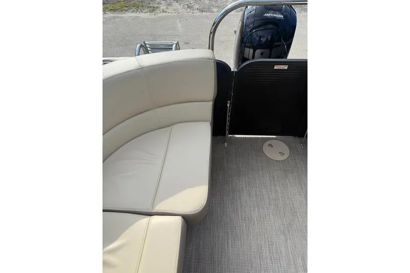 Slide: The Image of 2022 Manitou 23 Aurora LE RF boat interior with beige seating and Mercury engine. - 7