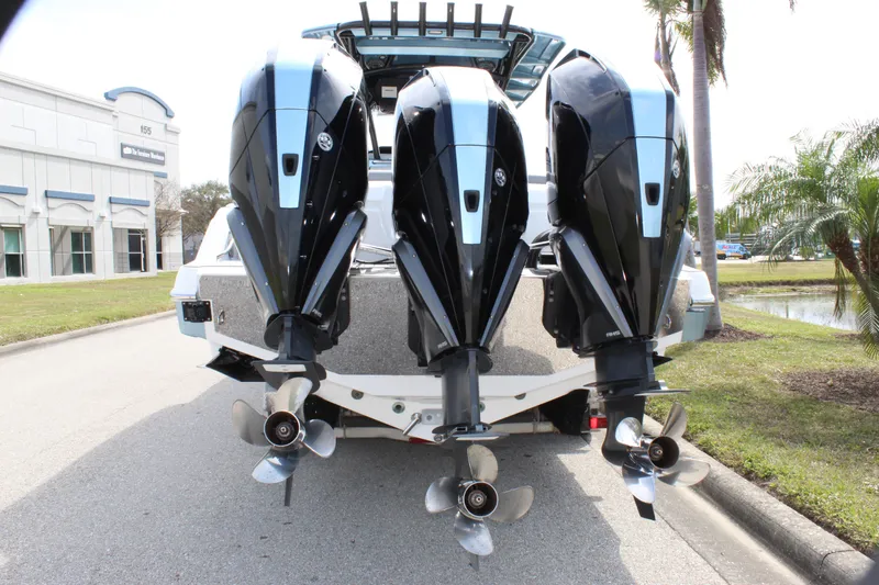 Slide: The Image of 2021 Nor-Tech 390 Sport Center Console with triple outboard engines, parked outdoors. - 12