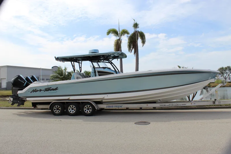 Slide: The Image of 2021 Nor-Tech 390 Sport Center Console boat on a trailer, parked near palm trees. - 15