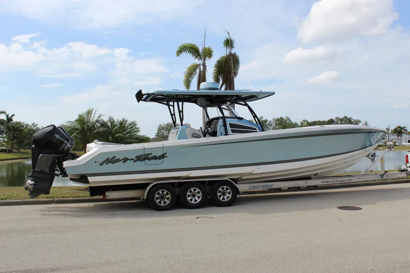Slide: The Image of 2021 Nor-Tech 390 Sport Center Console boat on trailer, parked near palm trees. - 16