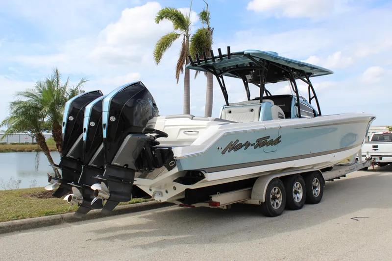 Slide: The Image of 2021 Nor-Tech 390 Sport Center Console boat on trailer, parked near palm trees. - 20