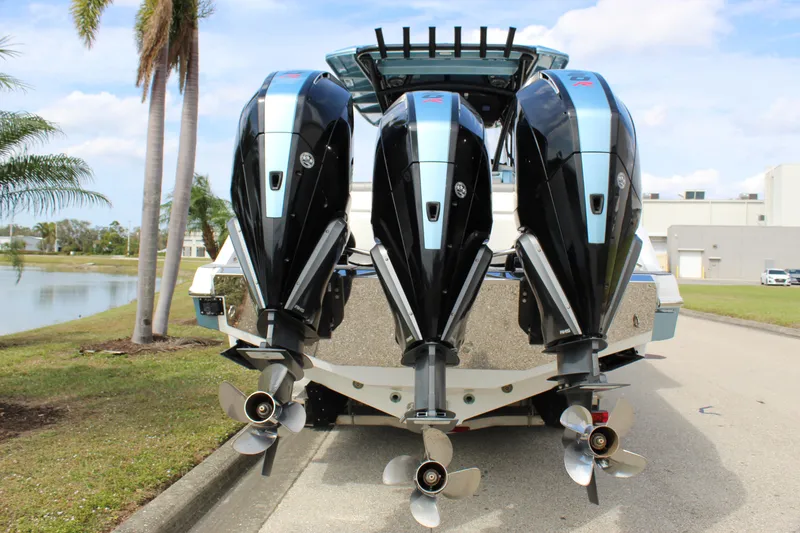 Slide: The Image of 2021 Nor-Tech 390 Sport Center Console with triple outboard engines, parked near a lake. - 23